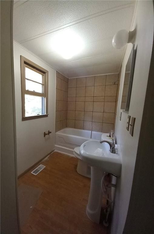 bathroom with visible vents, shower / tub combination, wood finished floors, a sink, and toilet