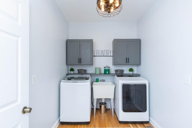 washroom featuring cabinets, separate washer and dryer, a chandelier, and light hardwood / wood-style floors