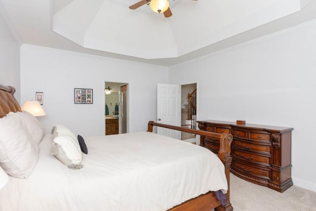 bedroom featuring ornamental molding, light colored carpet, ensuite bathroom, and a tray ceiling