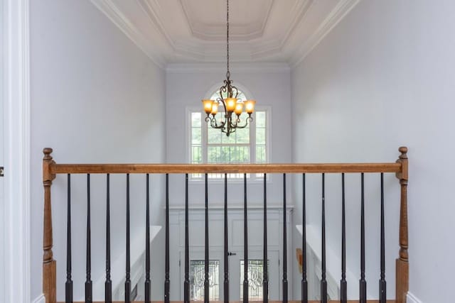 staircase with an inviting chandelier, crown molding, and a raised ceiling