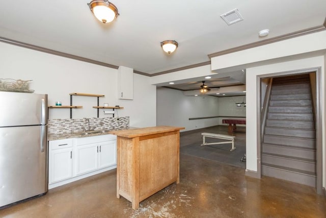 kitchen featuring sink, wooden counters, stainless steel refrigerator, tasteful backsplash, and white cabinets