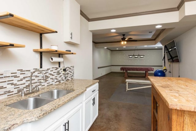 kitchen featuring sink, crown molding, white cabinetry, light stone counters, and decorative backsplash