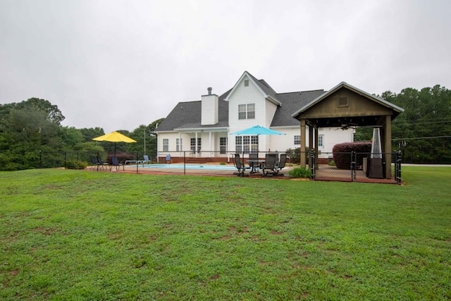 back of property featuring ceiling fan, a yard, a fenced in pool, and a patio