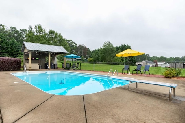 view of swimming pool with a diving board, an outbuilding, a patio area, and a lawn