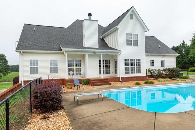 rear view of property with a fenced in pool and a patio area