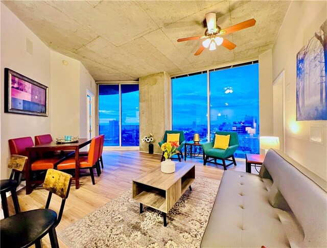 living room featuring expansive windows, light wood-type flooring, and ceiling fan