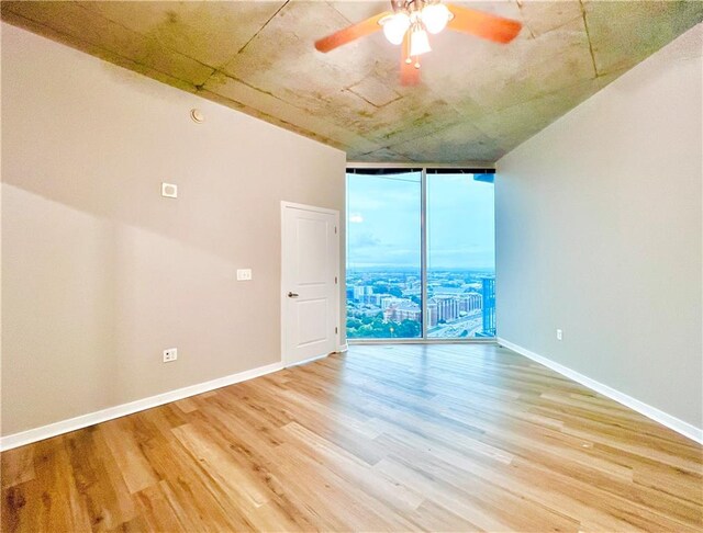 empty room featuring ceiling fan, hardwood / wood-style flooring, and floor to ceiling windows