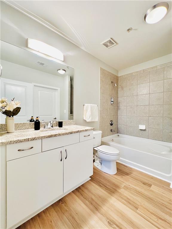 full bathroom featuring vanity, toilet, tiled shower / bath combo, and hardwood / wood-style floors