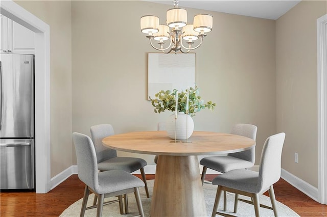 dining space featuring a chandelier, baseboards, and wood finished floors