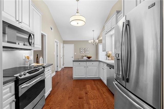 kitchen featuring a peninsula, vaulted ceiling, white cabinets, appliances with stainless steel finishes, and dark countertops