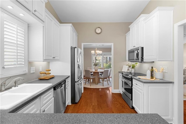 kitchen with dark wood-style floors, white cabinets, stainless steel appliances, and a sink