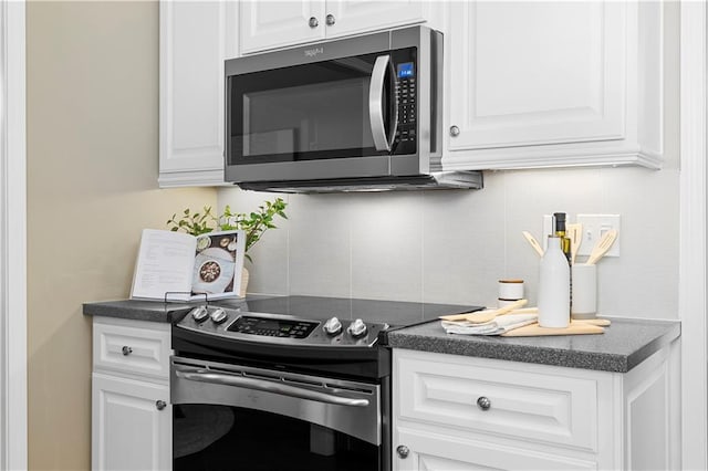 kitchen featuring dark countertops, white cabinetry, stainless steel appliances, and tasteful backsplash