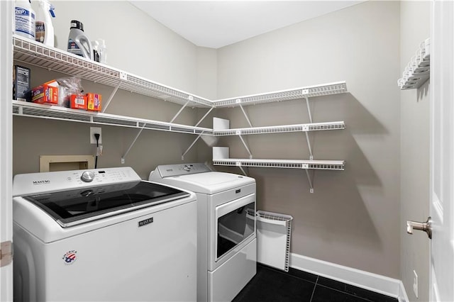 laundry room featuring dark tile patterned floors, laundry area, baseboards, and separate washer and dryer