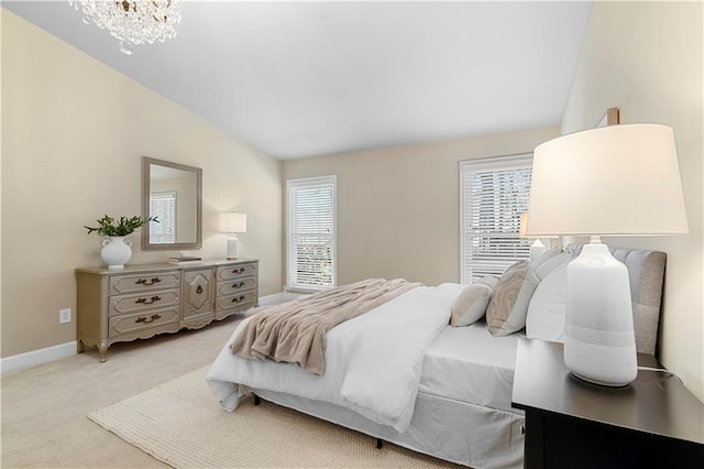 bedroom featuring baseboards, light colored carpet, an inviting chandelier, and vaulted ceiling