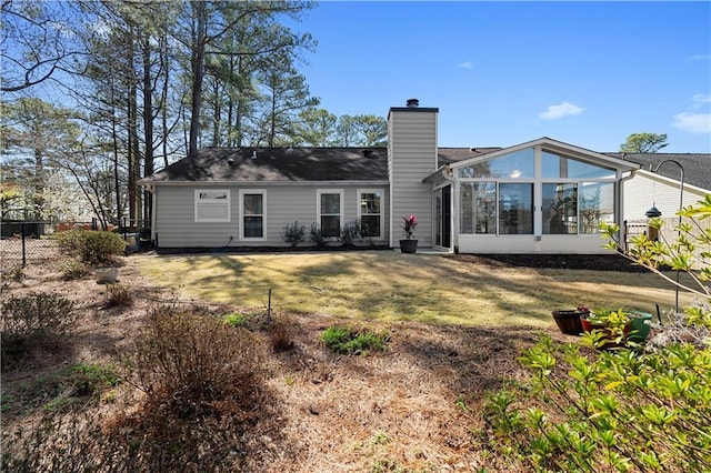 back of property with a yard, a sunroom, a chimney, and fence