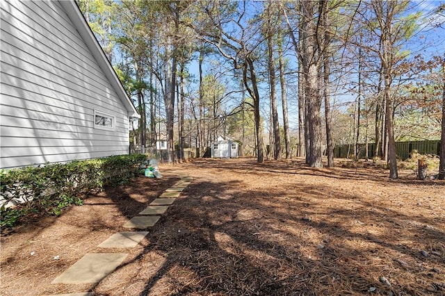 view of yard featuring an outdoor structure, fence, and a shed