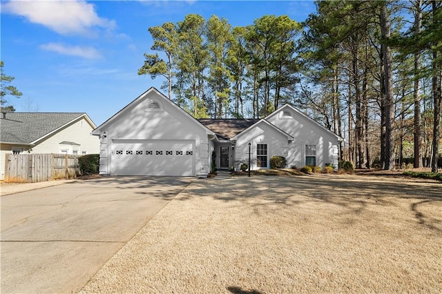 ranch-style house featuring a garage, concrete driveway, and fence