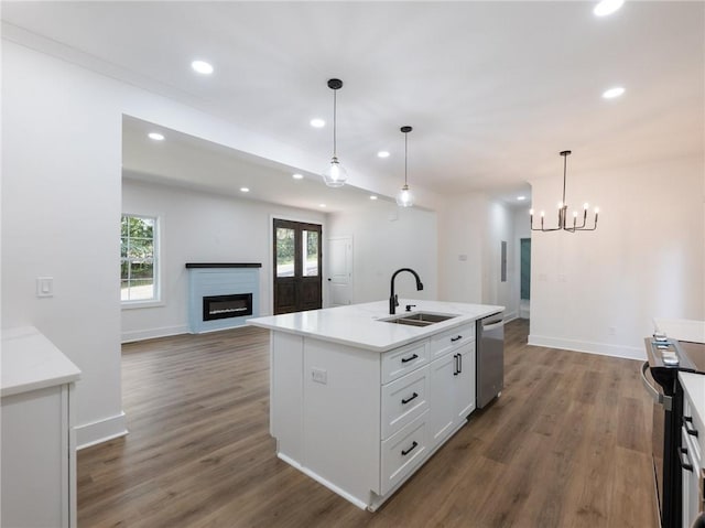 kitchen with appliances with stainless steel finishes, white cabinetry, an island with sink, decorative light fixtures, and sink