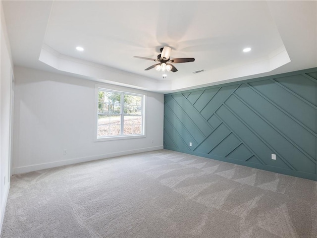 unfurnished room with light carpet, ceiling fan, and a raised ceiling