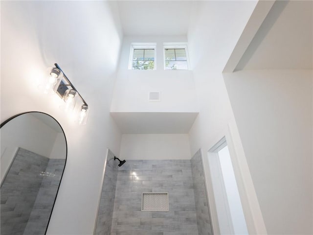 bathroom with tiled shower and a towering ceiling