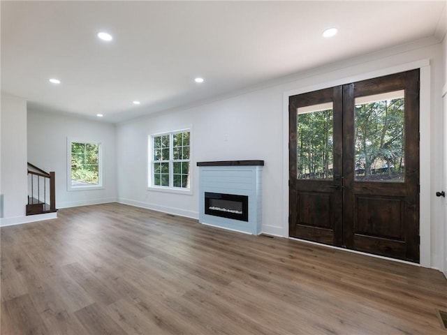 unfurnished living room with crown molding, hardwood / wood-style floors, and a wealth of natural light