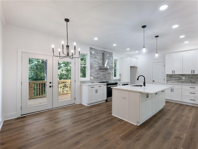 kitchen with stainless steel range with electric stovetop, a kitchen island with sink, wall chimney range hood, and white cabinetry