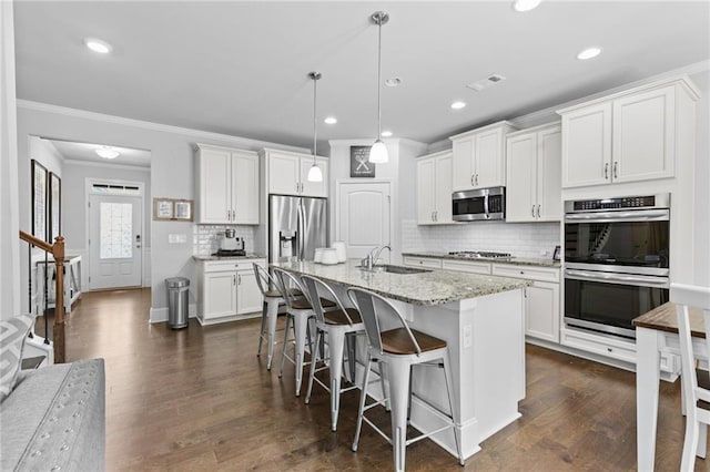 4568 Mantova Dr, Buford, GA 30519 - kitchen featuring appliances with stainless steel finishes, a sink, ornamental molding, a kitchen breakfast bar, and decorative backsplash