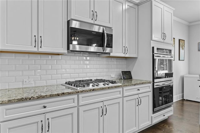 4568 Mantova Dr, Buford, GA 30519 - kitchen featuring appliances with stainless steel finishes, ornamental molding, dark wood-type flooring, tasteful backsplash, and light stone counters