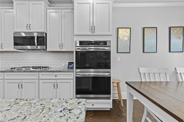 4568 Mantova Dr, Buford, GA 30519 - kitchen with stainless steel appliances, crown molding, light stone counters, dark wood-style flooring, and decorative backsplash
