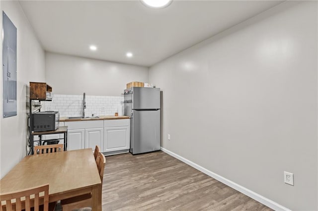 4568 Mantova Dr, Buford, GA 30519 - kitchen featuring freestanding refrigerator, backsplash, white cabinets, a sink, and light wood finished floors