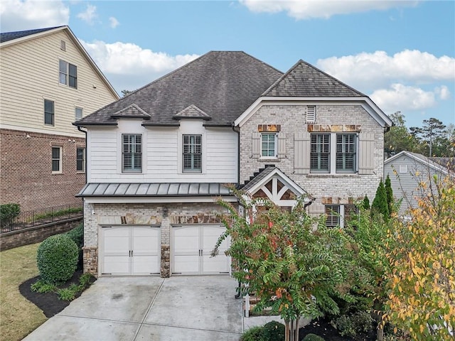 french country home with metal roof, a garage, brick siding, driveway, and a standing seam roof