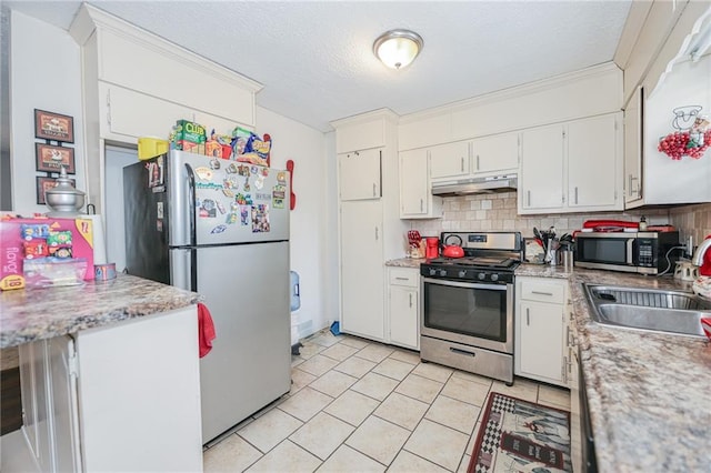 kitchen with tasteful backsplash, stainless steel appliances, under cabinet range hood, white cabinetry, and a sink