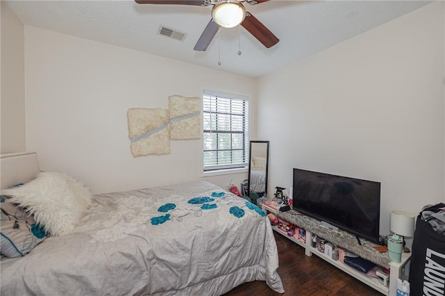 bedroom featuring ceiling fan, visible vents, and wood finished floors