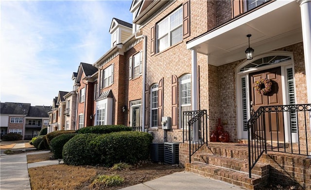 entrance to property with a residential view, brick siding, and central AC unit