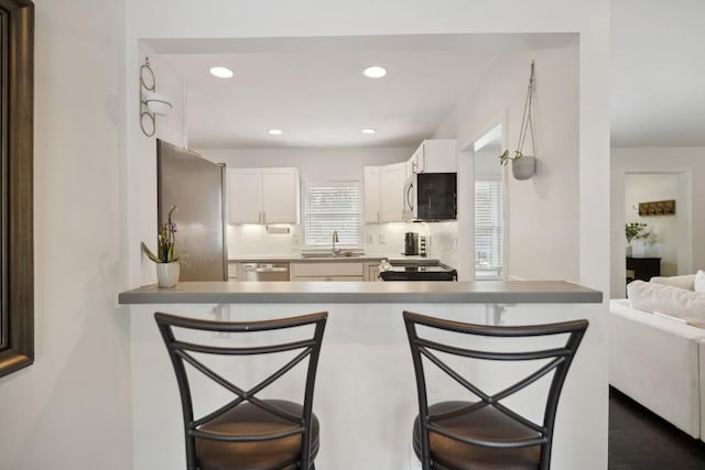 kitchen featuring white cabinetry, a kitchen breakfast bar, appliances with stainless steel finishes, and kitchen peninsula