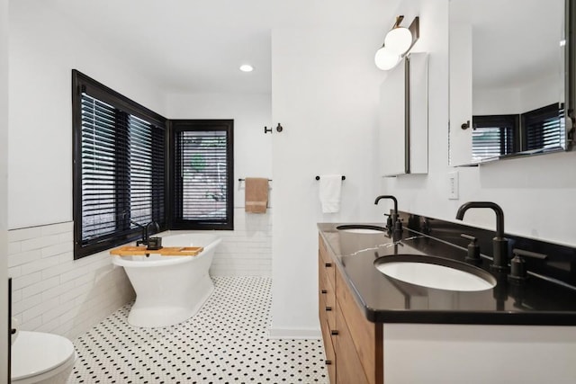 bathroom featuring vanity, a tub to relax in, tile patterned floors, and tile walls