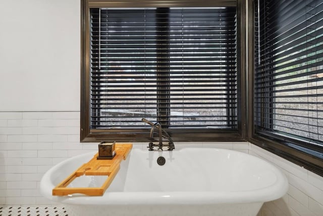 bathroom with a washtub and tile walls