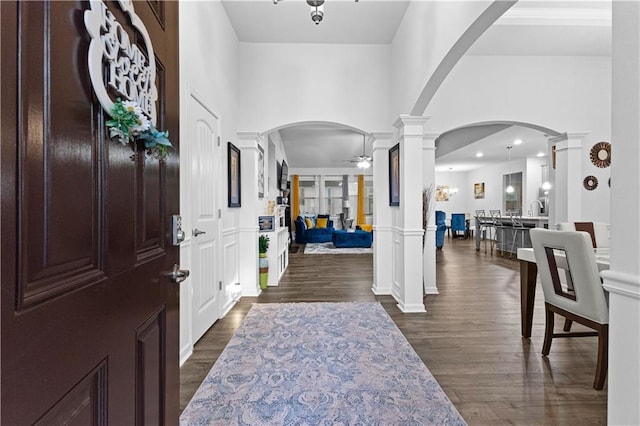 foyer entrance with ornate columns, dark hardwood / wood-style flooring, a high ceiling, and ceiling fan