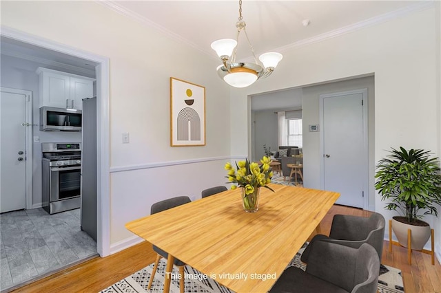 dining space featuring baseboards, ornamental molding, and light wood finished floors