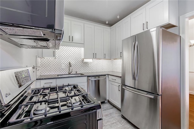 kitchen featuring dark stone counters, a sink, white cabinets, appliances with stainless steel finishes, and backsplash