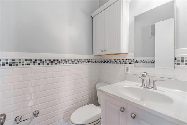 bathroom featuring a wainscoted wall, toilet, tile walls, and vanity