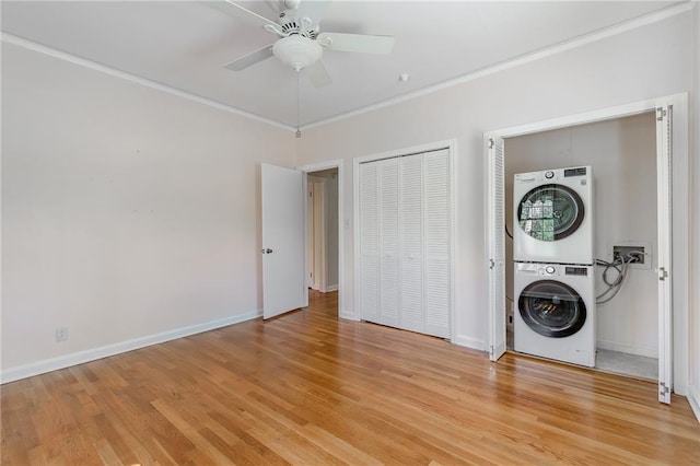 laundry area with light wood finished floors, ornamental molding, laundry area, and stacked washing maching and dryer