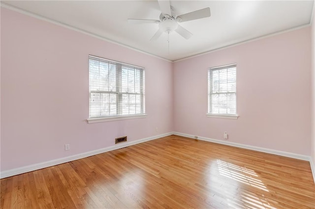 empty room with visible vents, baseboards, ornamental molding, light wood-style flooring, and a ceiling fan