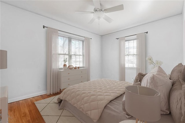 bedroom with a ceiling fan, wood finished floors, and baseboards