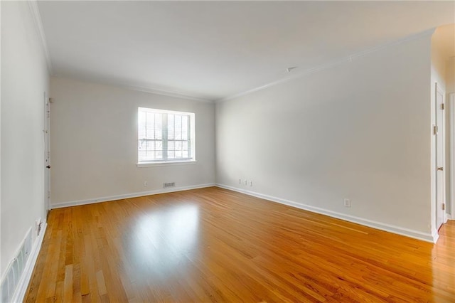 unfurnished room with visible vents, light wood-style floors, baseboards, and ornamental molding