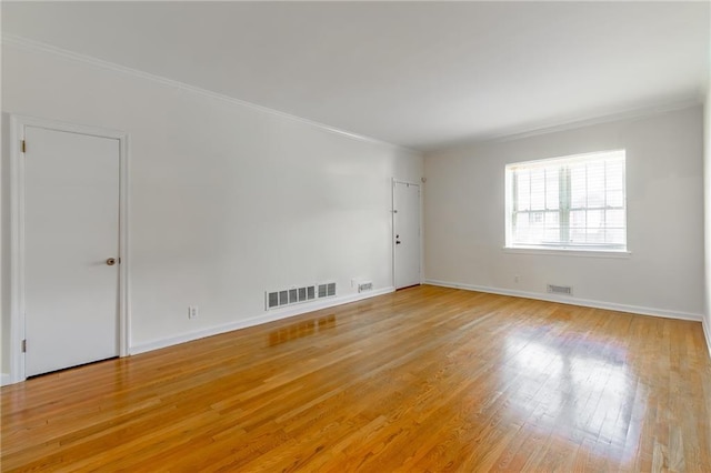 empty room with visible vents, baseboards, crown molding, and light wood-style floors