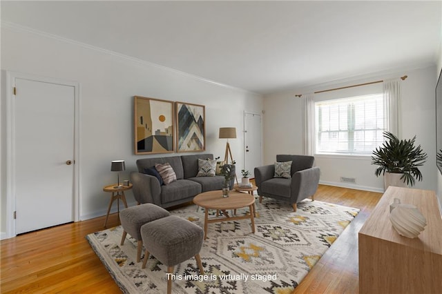 living area featuring visible vents, baseboards, light wood-style flooring, and ornamental molding