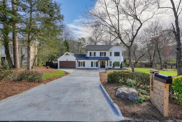 view of front of house with driveway, board and batten siding, and fence