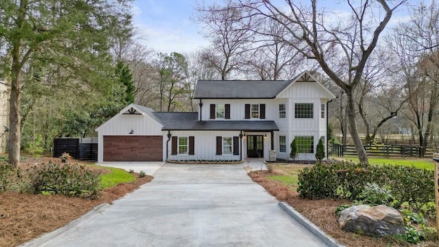 modern farmhouse with a garage, fence, concrete driveway, roof with shingles, and board and batten siding