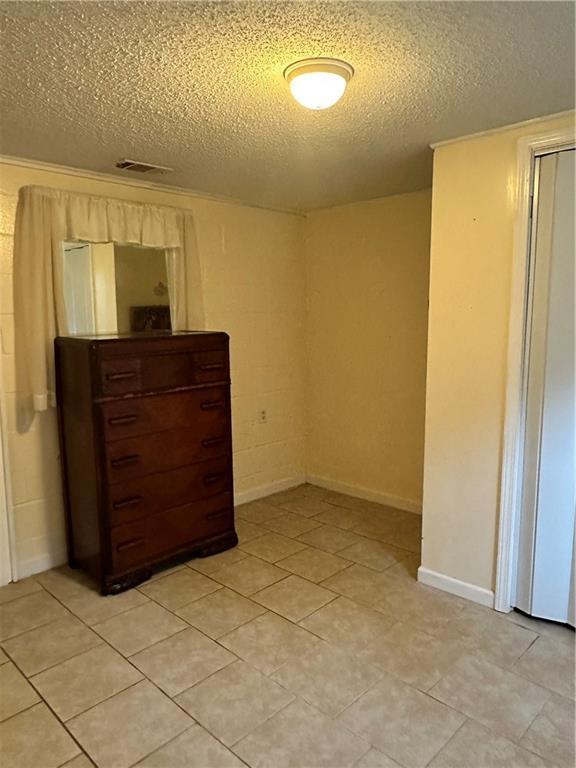 tiled bedroom featuring a textured ceiling